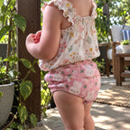 Toddler seen from behind in pink bunny-print training underwear on a sunny garden patio